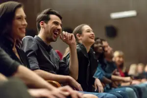 Row of people smiling and laughing at performer