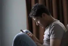 Side view of man looking down at his smartphone in disbelief