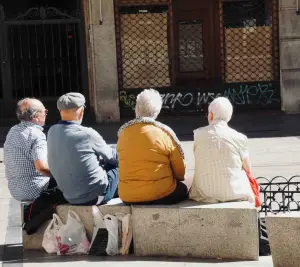 Back view of four older people sitting outdoors chatting