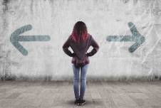 Woman stands in front of a wall with arrows pointed in opposite directions