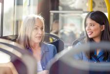 Two women talking and smiling on the bus