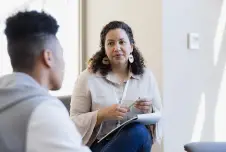 Therapist listening to her client, with her face visible and back of his head visible