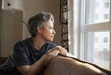 Woman sitting on the couch looking out the window with sad expression