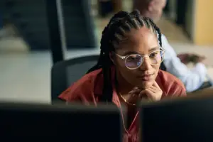 Woman thinking looking at her computer monitor