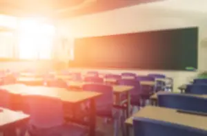 An empty modern classroom aglow from the afternoon sun peeking through its windows.