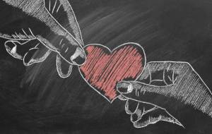 Illustration on chalkboard of two hands holding a heart