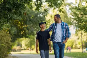 Father and son walking down a path with trees