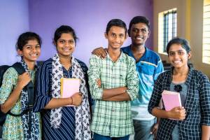 Five students smiling for the camera with books and backpacks