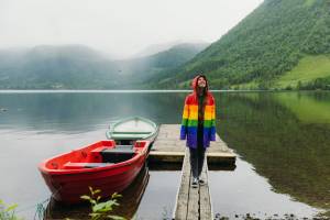 Woman in colorful coat standing in front of foggy lake with rowboats