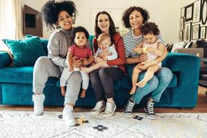 Three moms and their kids sitting on a couch