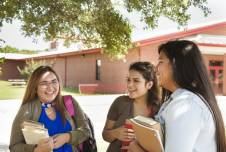 Three teen girls talking and smiling outside of school