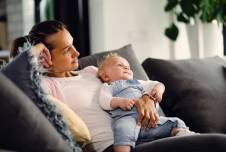 An image showing a mother reclining on a couch, holding her baby and looking relaxed and content