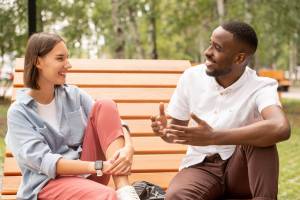 Two friends sitting on park bench talking