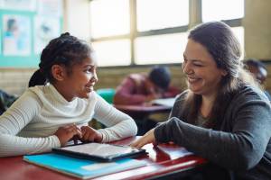 Teacher helping Black student, both smiling at each other
