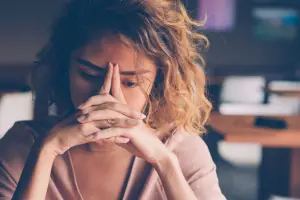 A stressed woman with her hands clasped in front of her face