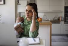 Stressed mom working on her computer holding her baby 