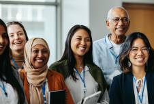 Group of women and one male coworker standing together and smiling