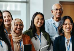 Group of women and one male coworker standing together and smiling