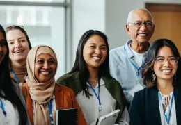 Group of women and one male coworker standing together and smiling