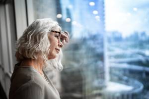 Woman leaning against a window looking serious