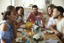 An image of a group of friends having a lively discussion around a dining table, suggesting a social setting where political views may be shared