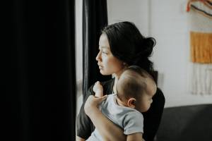 Mom holding baby looking out the window