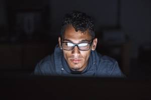 Man looking at a computer in a dark room