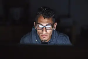 Man looking at a computer in a dark room