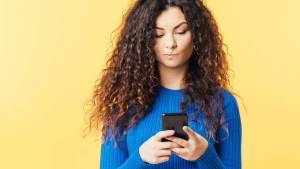 Woman staring indecisively at her phone.