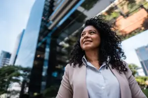 Businesswoman looking up and to the side, standing in front of buildings