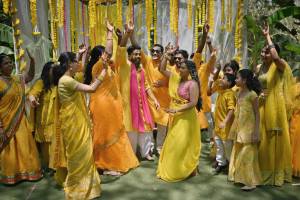 Family and friends dance with the bride and groom in a haldi ceremony