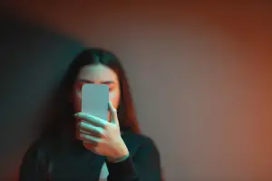 Woman sitting in the dark looking at her phone
