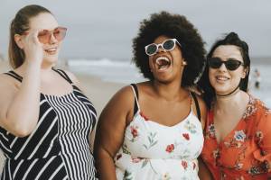 Three women laughing together at the beach.