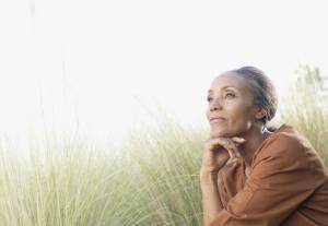 A woman is looking pensive while sitting in a field, surrounded by tall grass