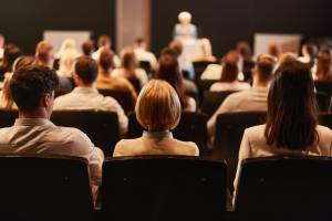 Back view of the audience at a seminar with speaker at the podium
