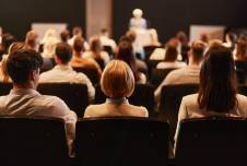 Back view of the audience at a seminar with speaker at the podium