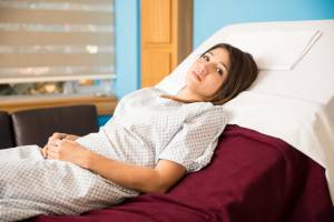 An image showing a worried female patient lying in a hospital bed.