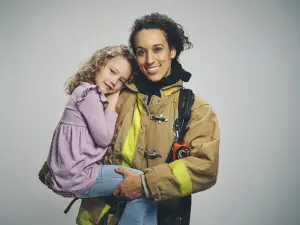 Firefighter holding young girl and smiling